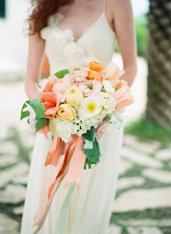 Bride holding colorful wedding bouquet in an elegant dress