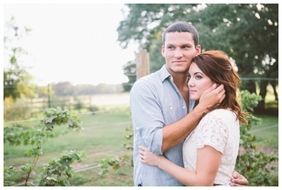 Engaged couple embracing in a vineyard setting