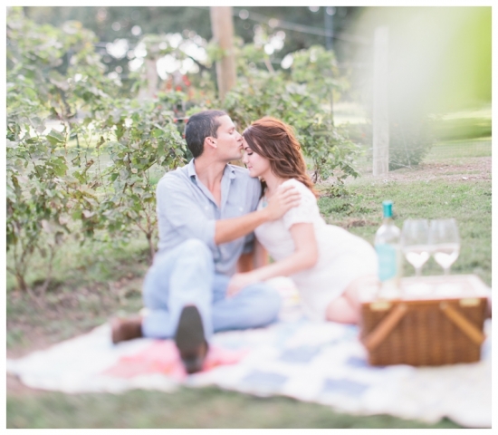 Couple enjoying picnic with wine in vineyard setting