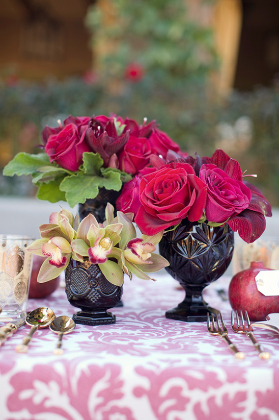 Red roses and orchids in dark vases