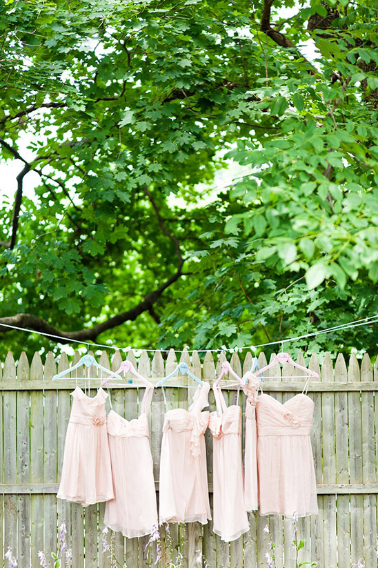 Pink bridesmaid dresses hanging on a fence outdoors
