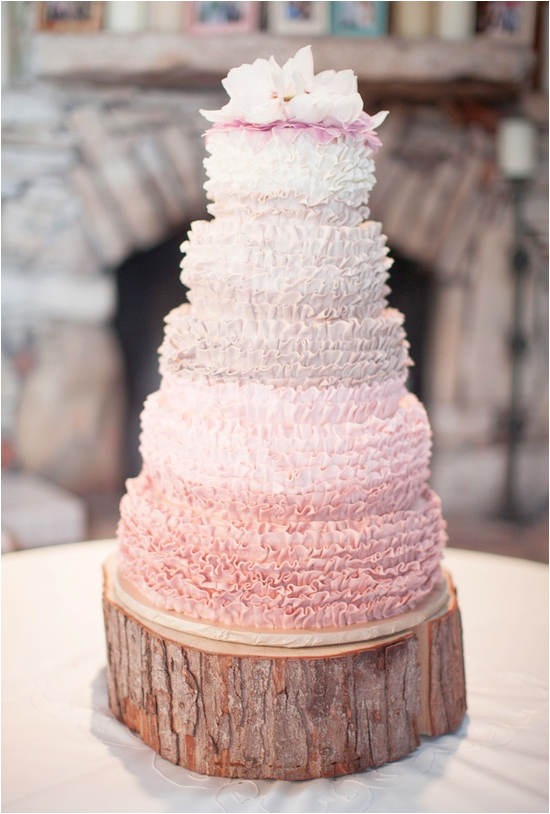 Elegant pink ruffle wedding cake on rustic wood slice