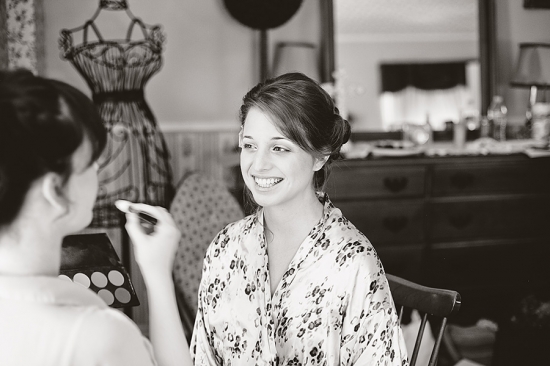 Smiling bride getting makeup done in black and white