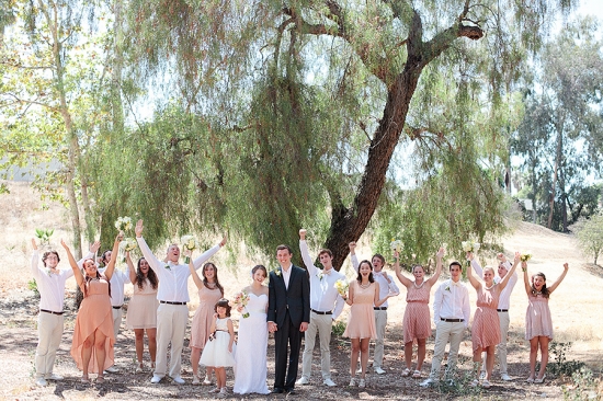 Happy wedding party cheers outdoors with bride and groom