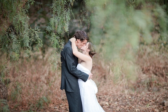 Bride and groom share a kiss in a natural setting