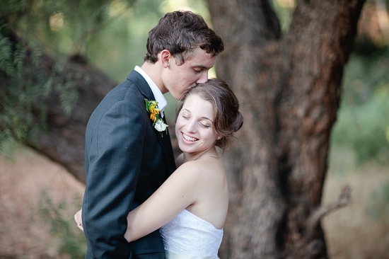 Happy bride kissed on forehead by groom at wedding
