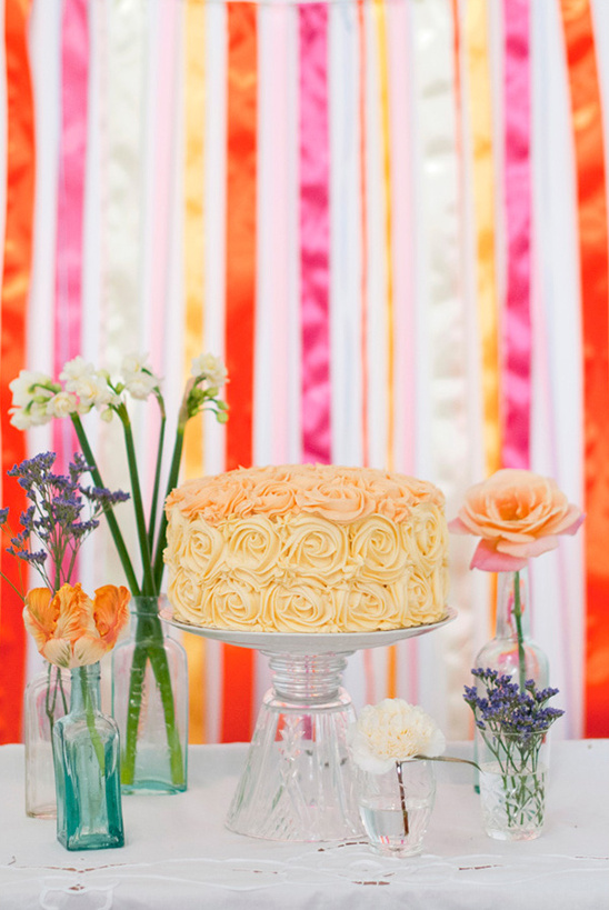 Cake with rose frosting and colorful ribbon backdrop