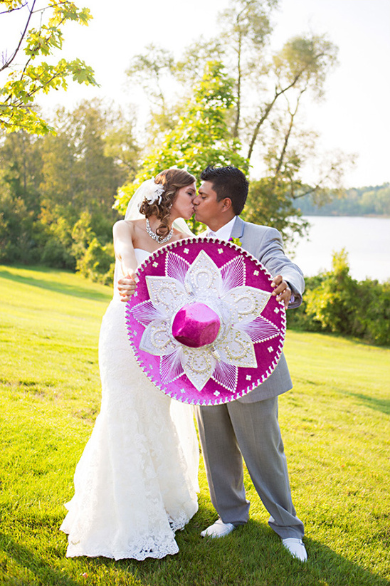 Bride and groom kiss behind a vibrant wedding sombrero