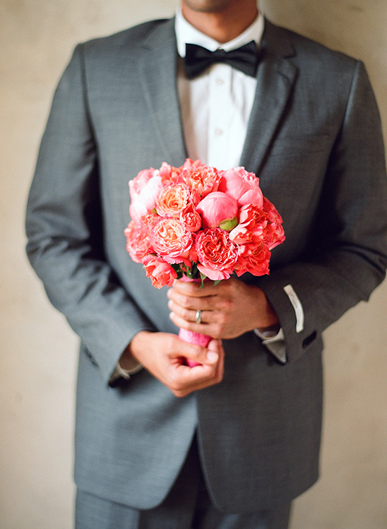 Man in suit holds vibrant pink bouquet
