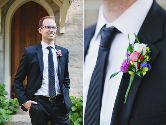 Groom smiles in a dark suit and floral boutonniere