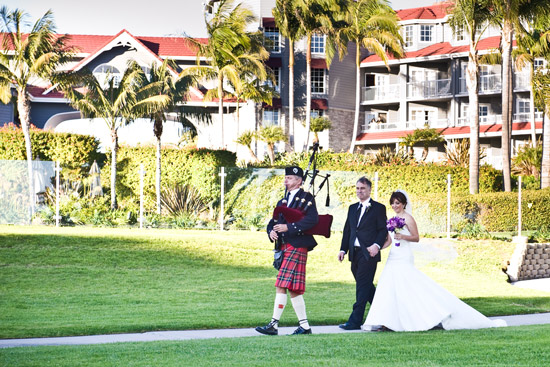 Bride and groom with bagpiper at outdoor wedding