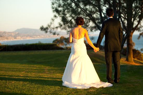 Bride and groom holding hands at sunset wedding view