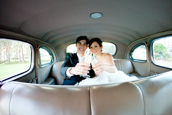 Happy newlyweds toasting in vintage car