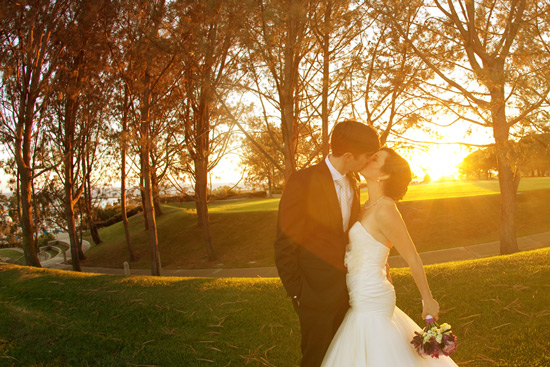 Golden sunset wedding kiss under trees
