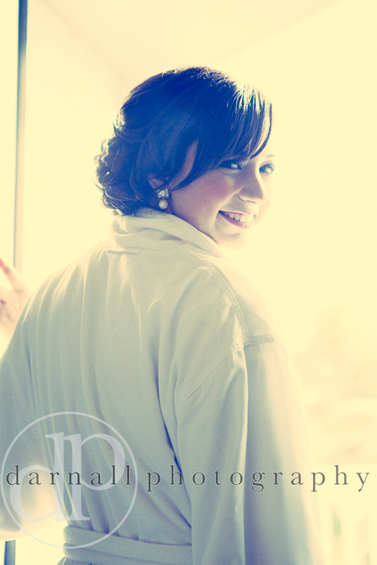 Bride looks back smiling in white robe morning light
