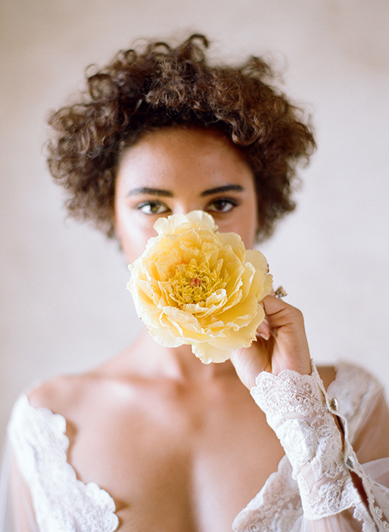 Woman holding yellow flower with lace gown detail