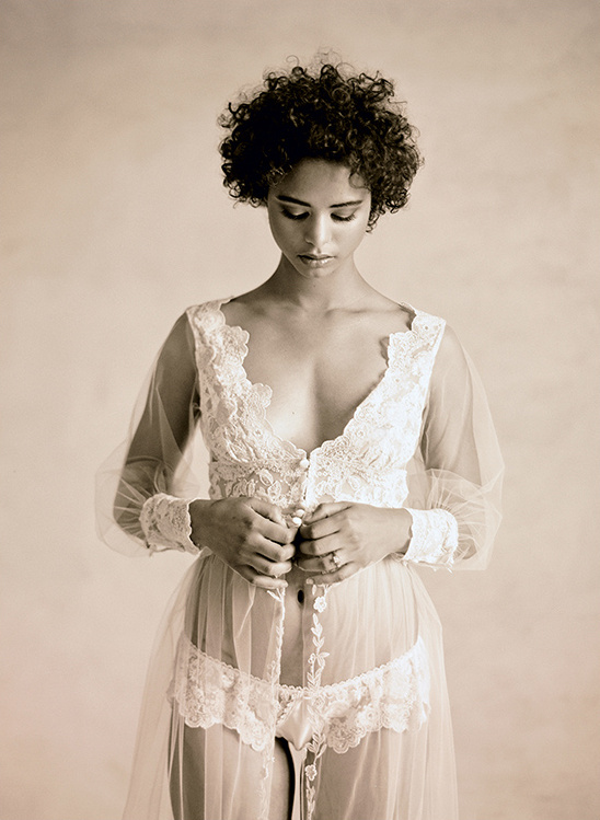 Woman in vintage lace lingerie buttons her robe
