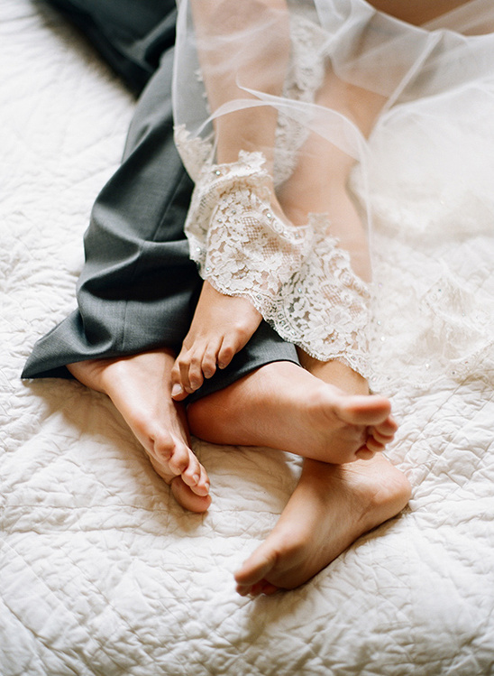 Newlyweds feet entwined on a white wedding bed