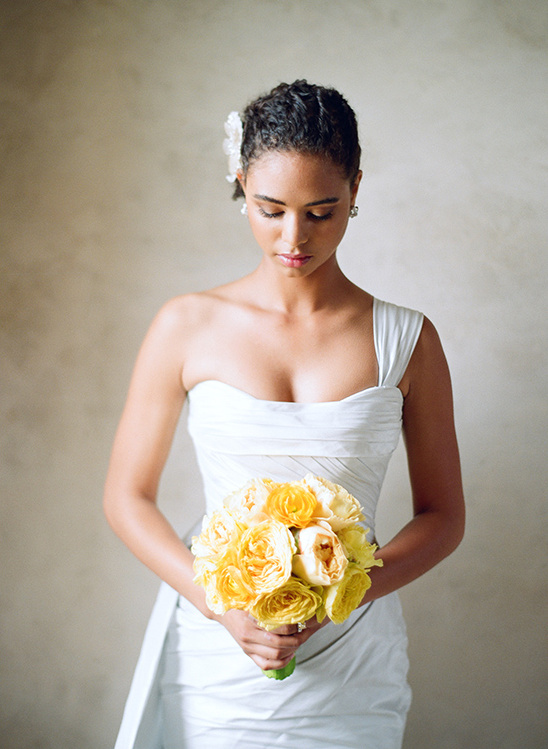 Bride in white dress holding yellow roses bouquet