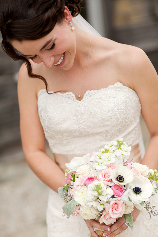 Happy bride in lace gown holding her wedding bouquet