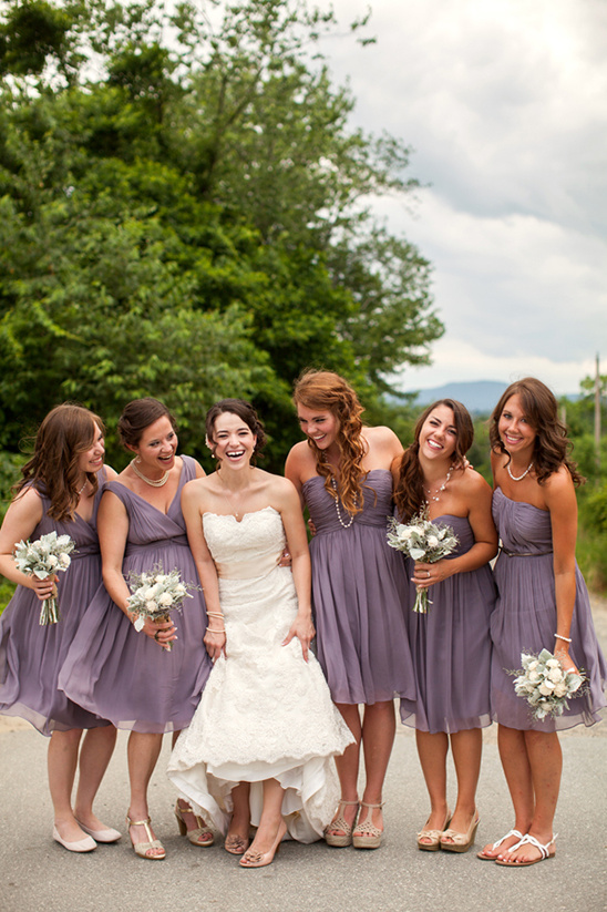 Bride and bridesmaids in lavender dresses smiling outdoors