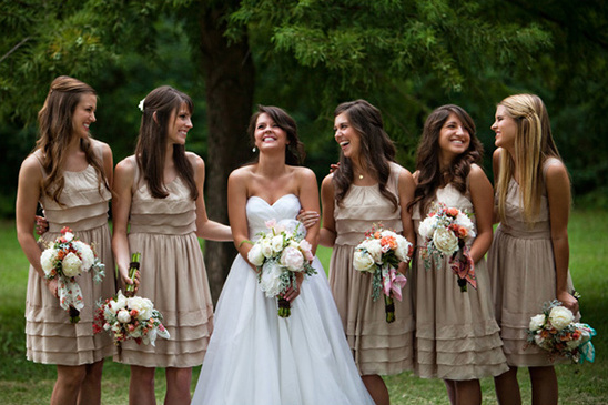 Bride and bridesmaids in tan dresses with bouquets