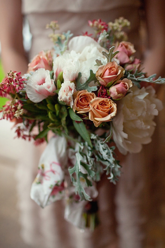 Bride holding a peach and white flower wedding bouquet