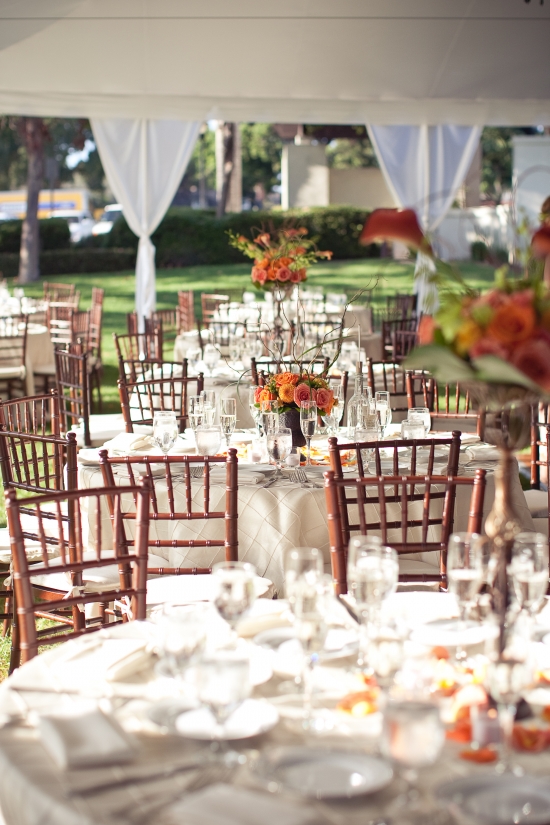 Outdoor wedding reception tables with orange flowers