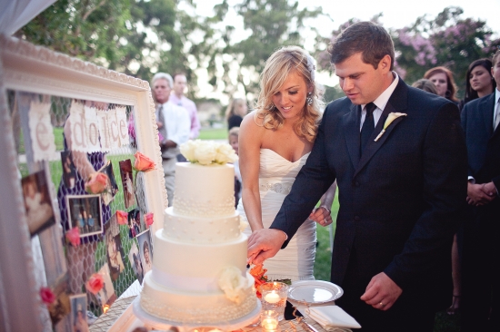Couple cutting wedding cake outdoors