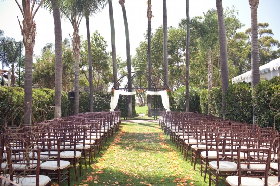 Outdoor wedding ceremony seating under palm trees
