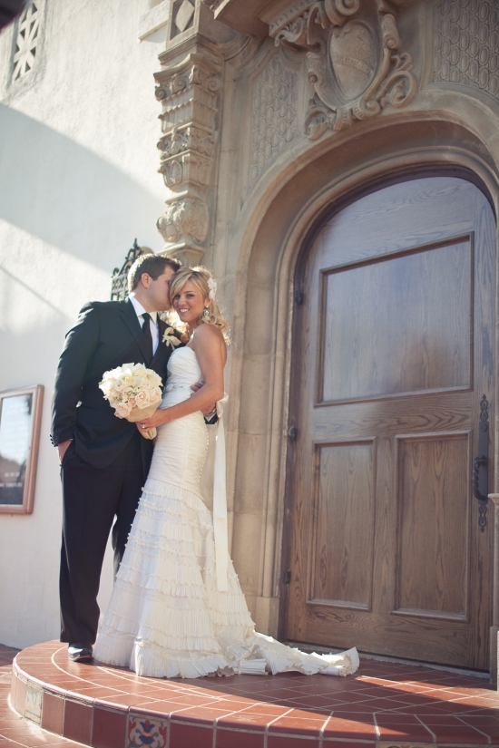 Happy wedding couple posing by church door