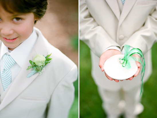 Ring bearer in cream suit holding pillow with rings