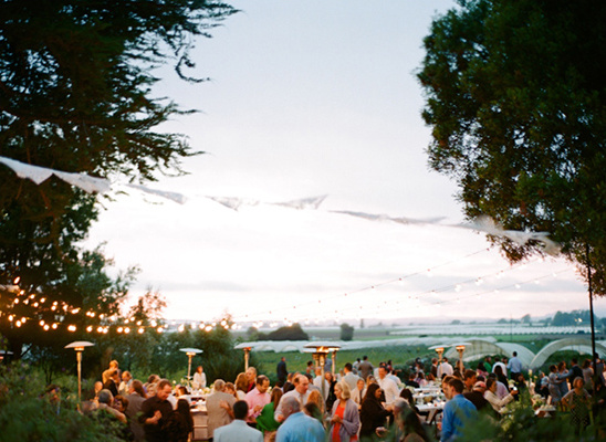 Outdoor wedding reception with guests enjoying sunset