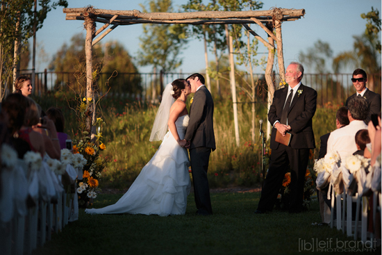 Bride and groom share a kiss at outdoor wedding ceremony