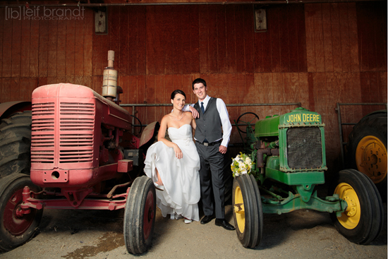Bride and groom pose with vintage tractors wedding photo