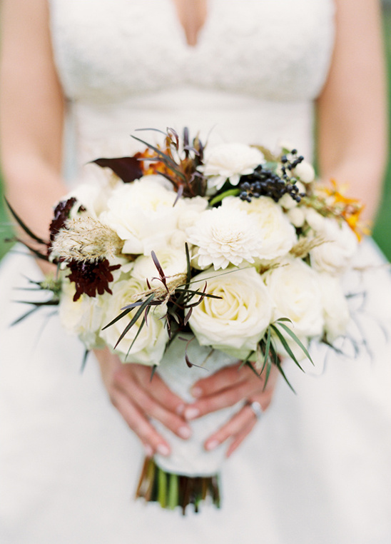 Bride holds elegant white rose wedding bouquet close