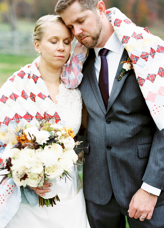 Newlyweds share a quilt at their outdoor wedding