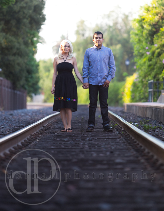Couple holding hands on train tracks