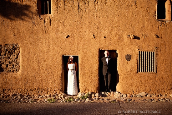 Couple in wedding attire adobe wall