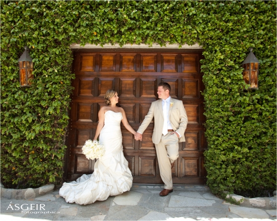 Bride and groom hold hands on wedding day by wooden door