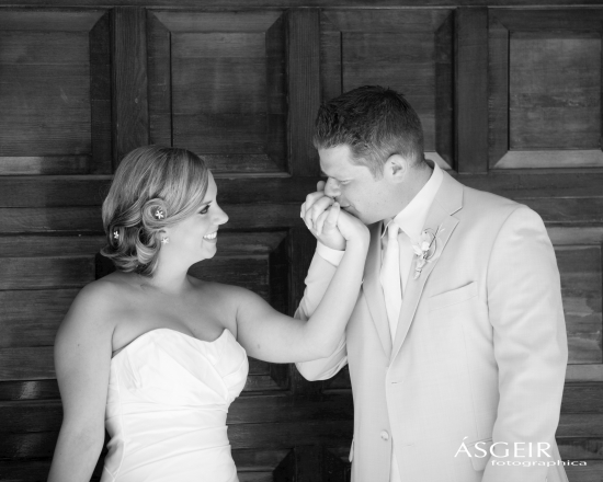 Bride smiles as groom kisses her hand wedding day