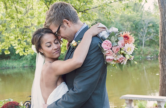 Couple embraces by lake, wedding day