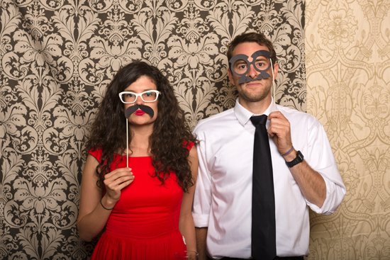 Couple poses with funny mustaches in a photo booth