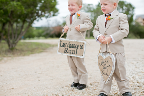 Ring bearers at a wedding holding signs for the bride