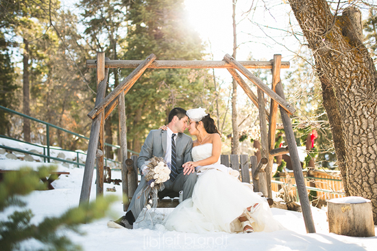 Bride and groom embrace on snowy swing
