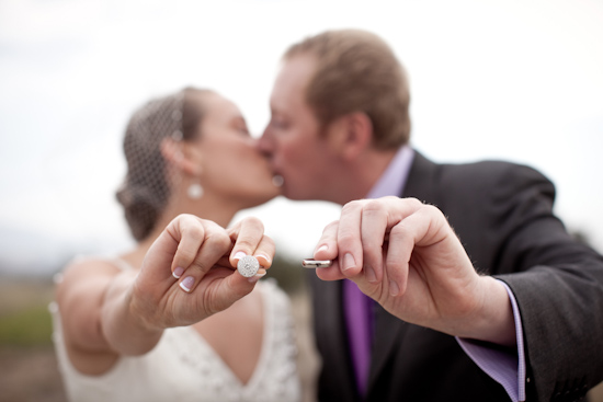 Bride and groom kissing, holding wedding rings
