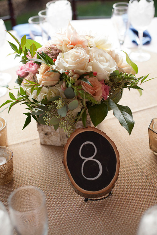 Table eight centerpiece: rustic wood slice with floral arrangement