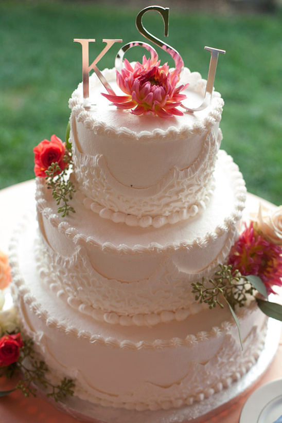 Three-tiered wedding cake with lace detailing and initials