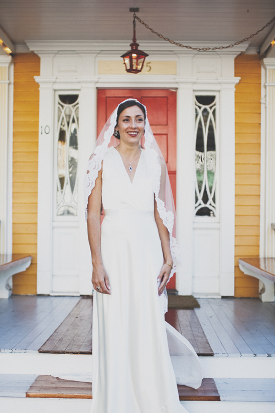 Bride in white dress, veil, posing on porch