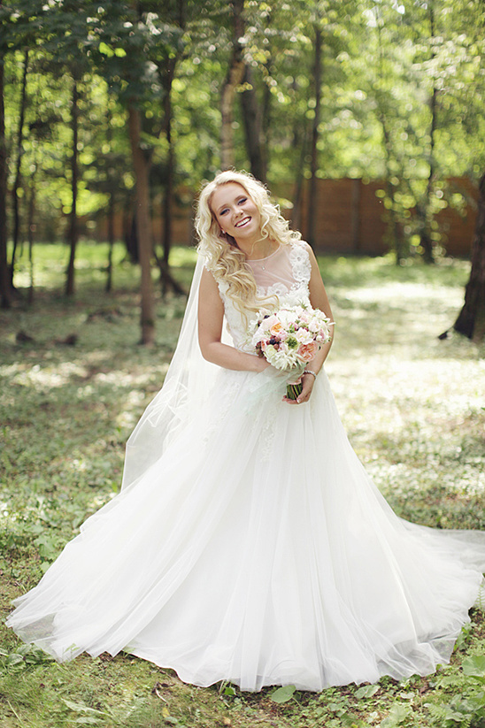 Smiling bride in flowing white wedding gown outdoors